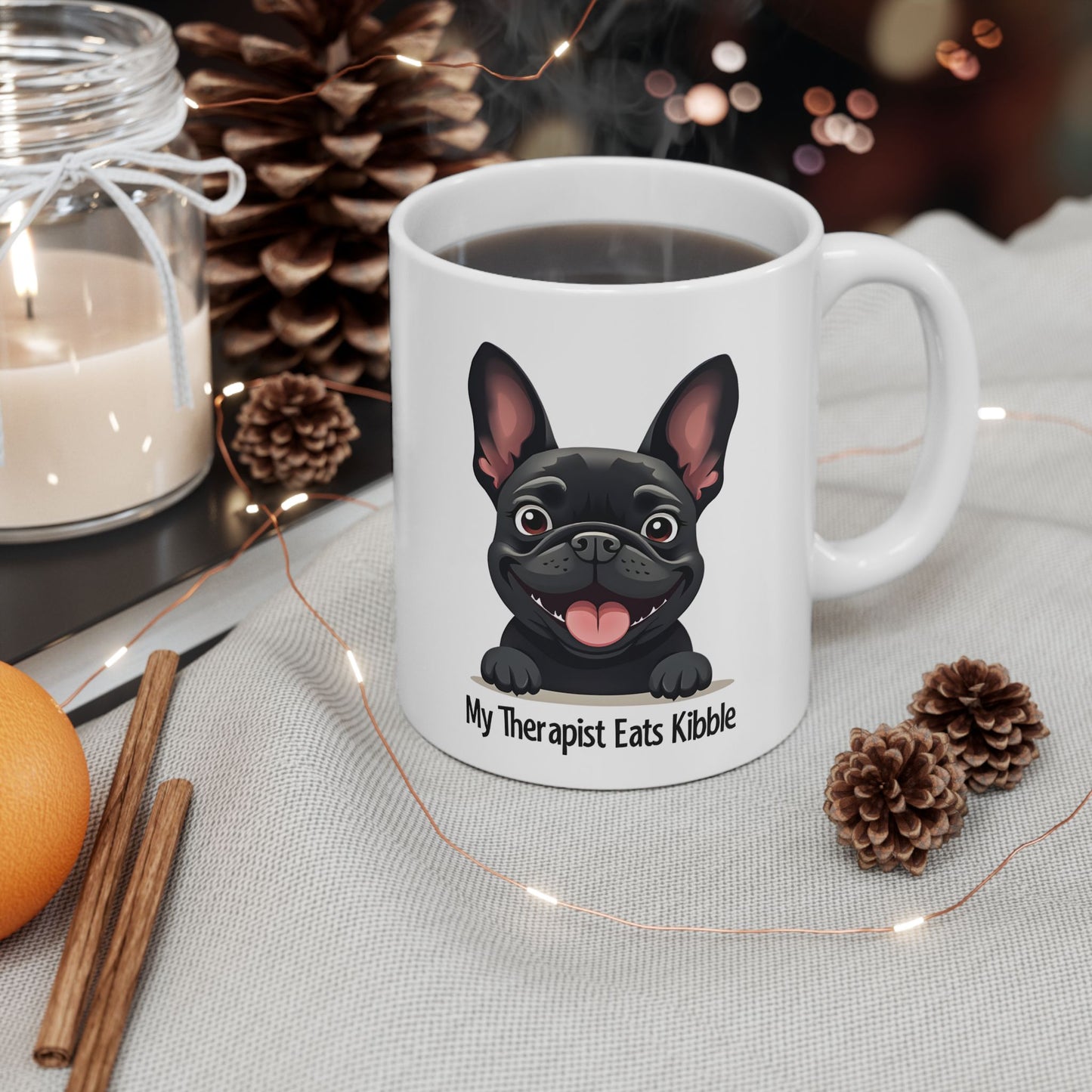 White mug with a black dog illustration and text, surrounded by decorative items on a table.